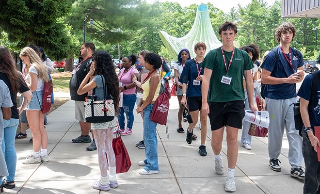 Student group walking/gathering on campus in summer sunshine near Alex and Ani building