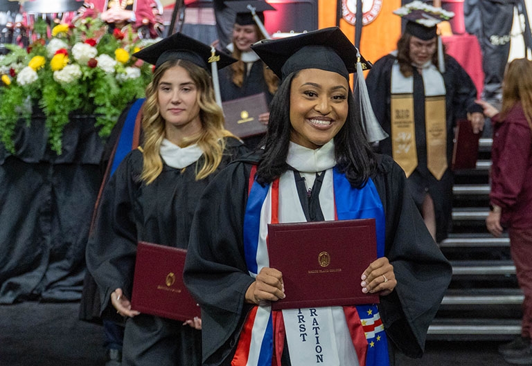 Graduates coming off of the stage with diplomas