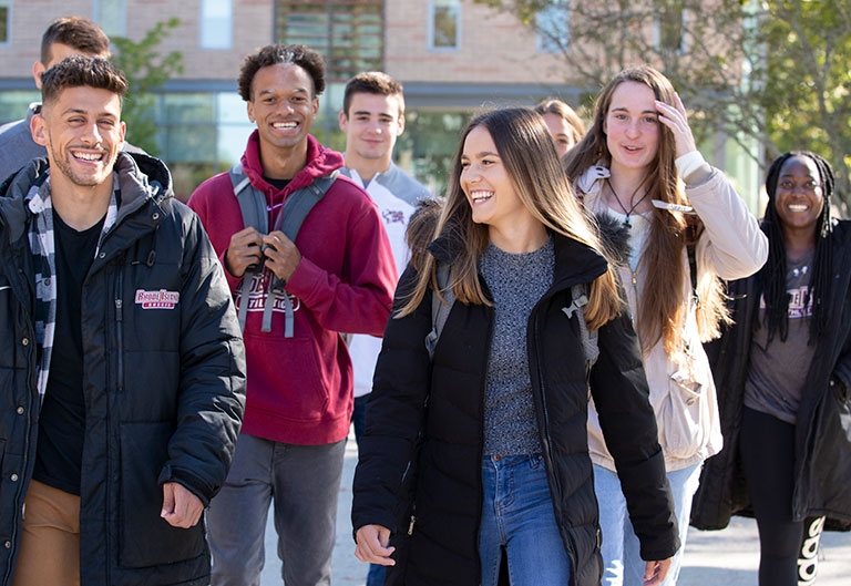Group of happy students walking on the quad in the sunshine