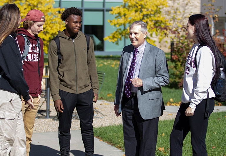 President Jack R. Warner speaking outside, in the fall, to a small group of students