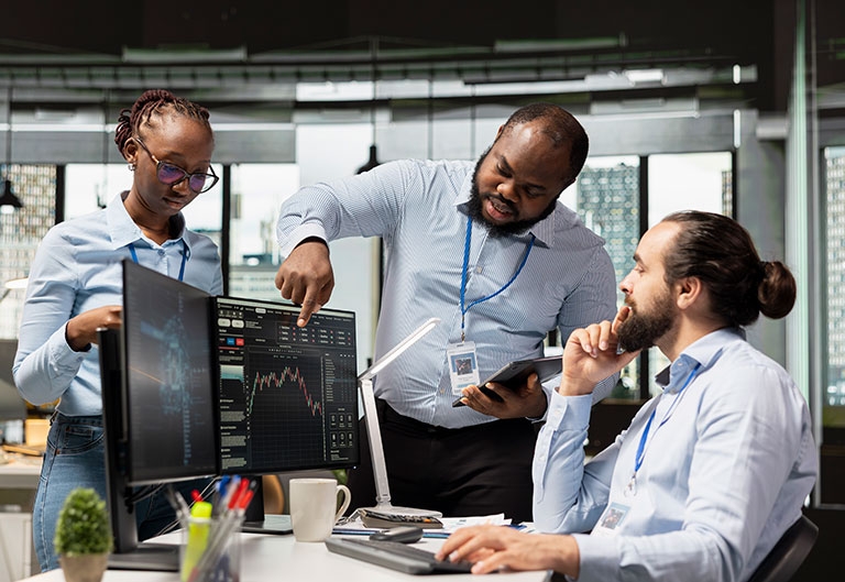 Stock brokers working together, looking at stats on computer