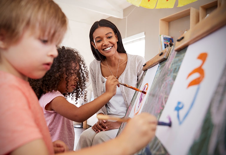 Art teacher watches two kids painting