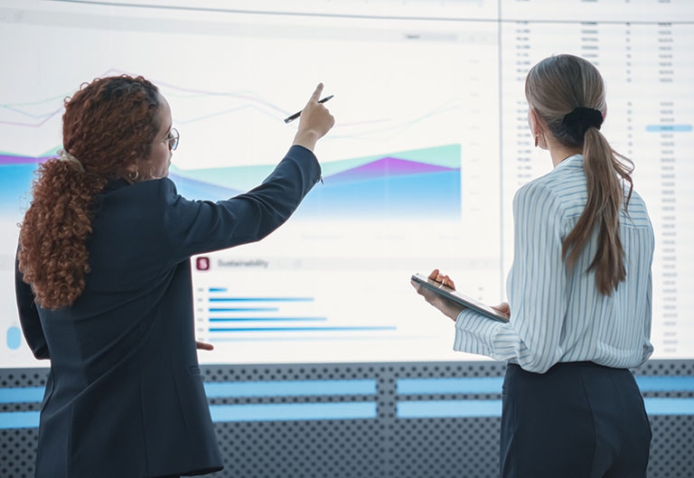 Data scientists discussing large screen of data and charts