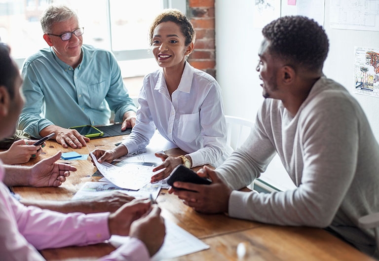 Diverse coworkers working around a table, happily