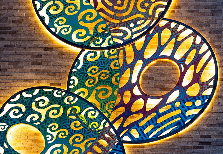 Full Circle sculpture, by Edwin Andrews, lit up on the side of Craig-Lee building