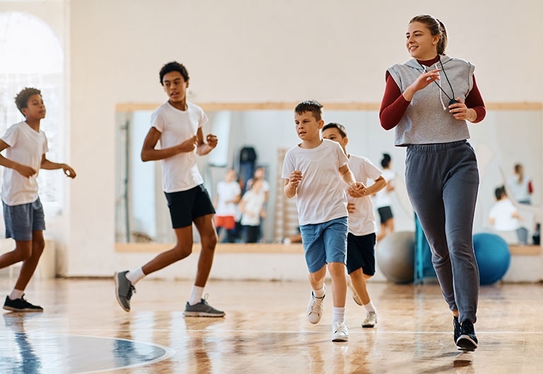Gym teacher running with students in gym