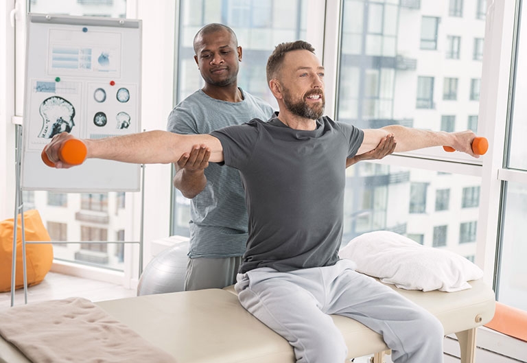 Health professional helping a patient lift dumbbells