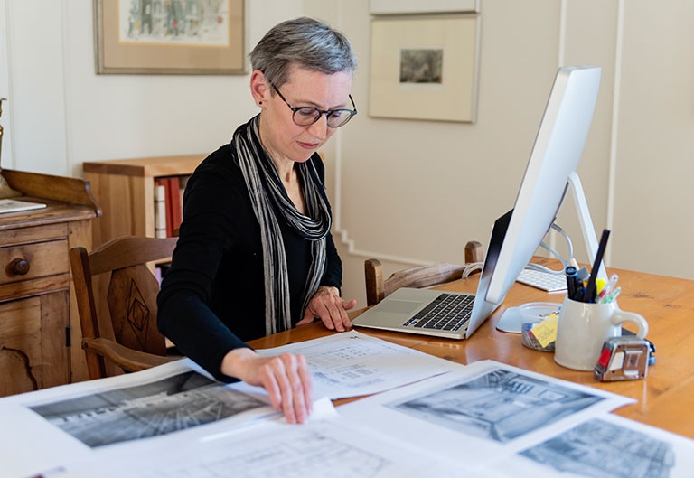Historian working at desk with documents and computer