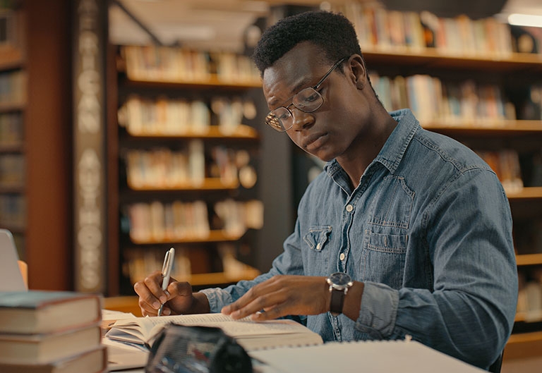 Man working in library, surrounded by books