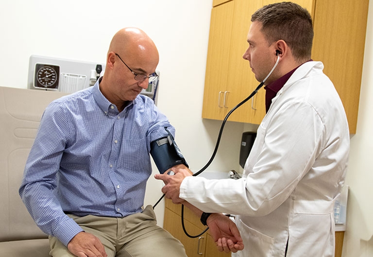 Nursing student taking patient's blood pressure using blood pressure cuff and stethoscope