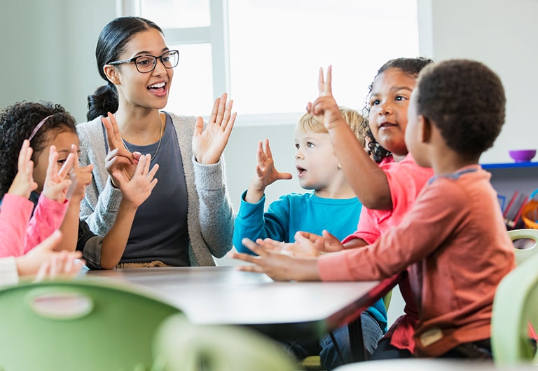 Preschool teacher working on counting with students at table