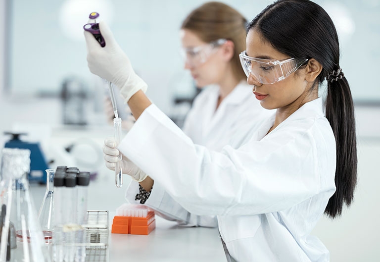 Scientists working in lab, putting liquid in test tubes