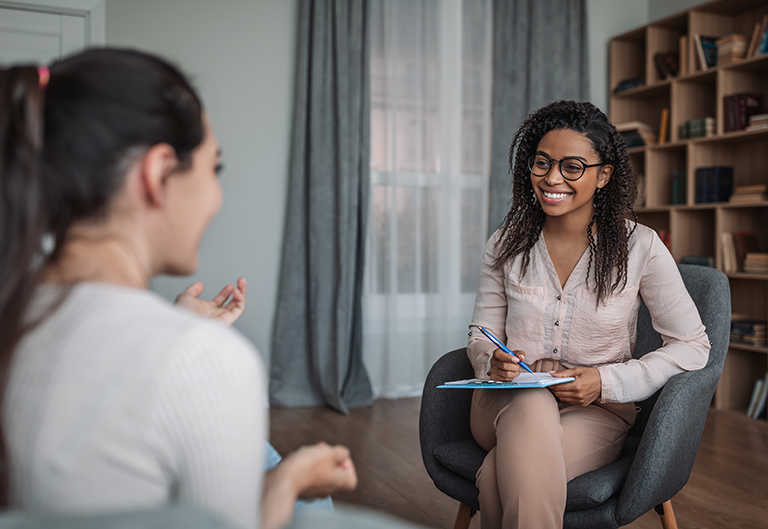 Clinical Psychologist meeting with a client, listening and writing while smiling