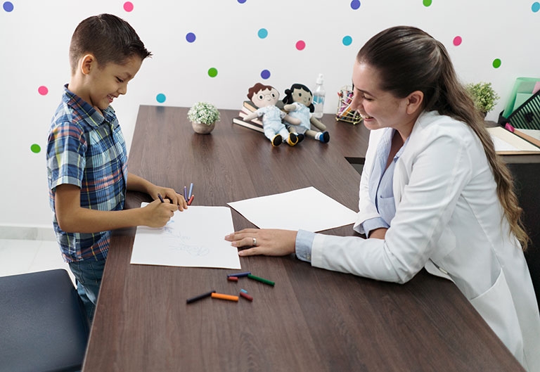 School psychologist working with little boy happily drawing