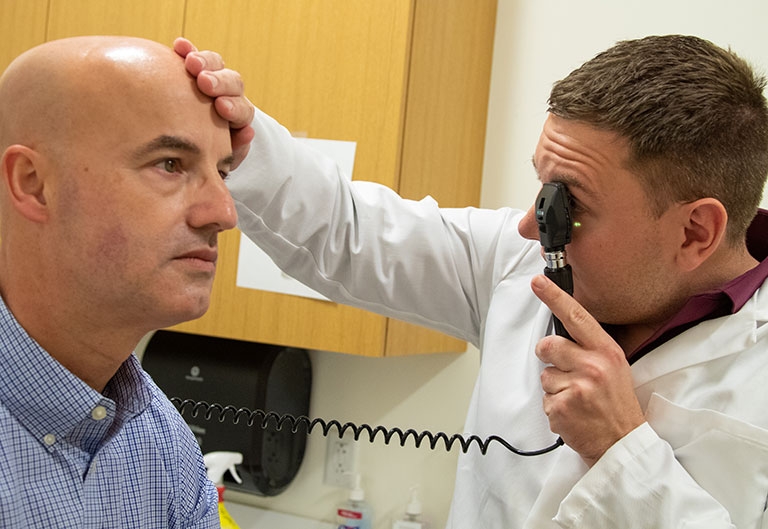 Nursing student checking patient's eyes