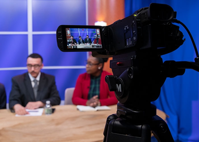 Raymond Baccari sitting with guests at Anchor newsdesk