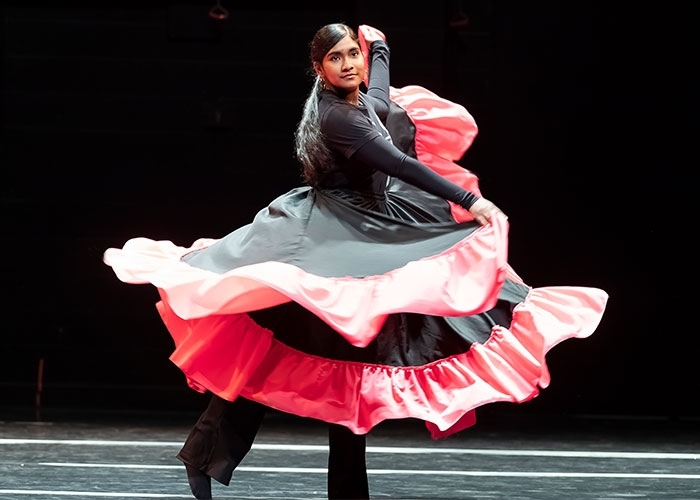Dance major, Andreina Mendoza in motion with layers of costume twirling around her