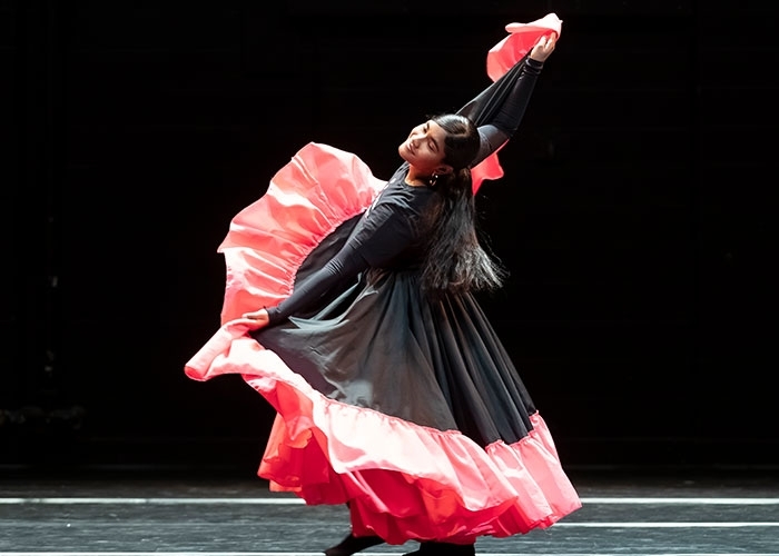 Dance major, Andreina Mendoza reaching out full span holding her costume while dancing