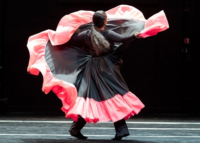 Dance major, Andreina Mendoza in motion with costume forming a C shape around her