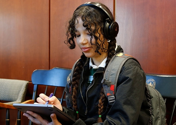Elizabeth Turbi working on a tablet with headphones on