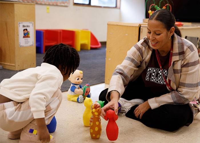 Apprentice, Rosa Goncalves, working with young student in class, on floor