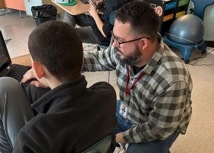 Paraprofessional, Robert Boyd, working with student in class, on laptop