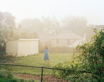 Women standing in a yard with a white house and shed nearby
