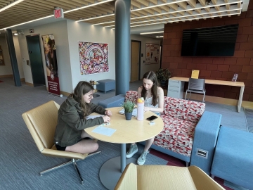 Older children writing at a table in a modern lobby