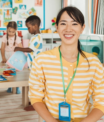 Early childhood education teacher with children in background in classroom