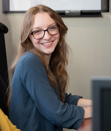Female student smiling in Finance Lab at computer