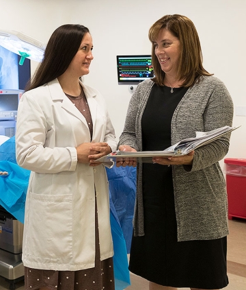 Kara Misto talking with nursing student while holding open binder