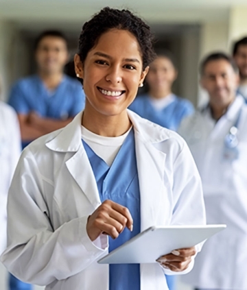 Medical professional with tablet and several other medical professionals in background