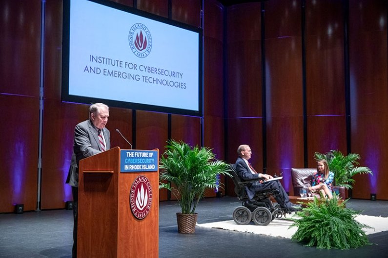 President Warner at podium with U.S. Representative Jim Langevin and Director of the Cybersecurity and Infrastructure Security Agency (CISA) Jen Easterly
