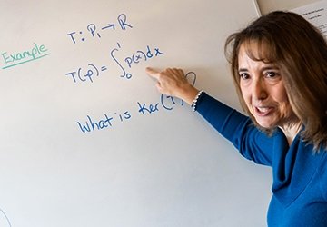 Lisa Humphreys teaching, doing a math equation on a whiteboard