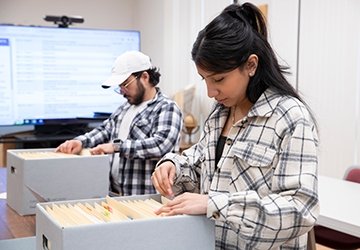 Two political science students looking through boxes of files
