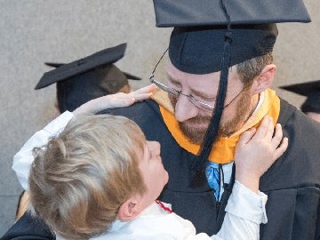 Graduate in cap and gown, holding child