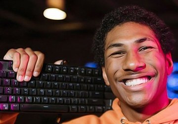Male student smiling, holding up a keyboard