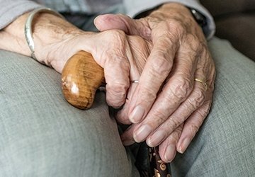 Hands of elderly person holding cane