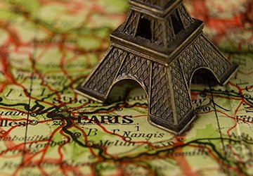 Model of Eiffel Tower sitting on map, marking Paris