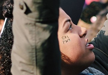 Person at rally with girl power temporary tatoo on face