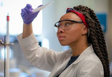 Student in biology lab looking at specimen in lab coat