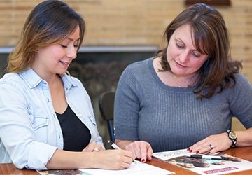 Two people writing promotional material together at a table