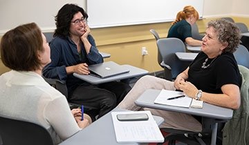 Faculty talking while sitting at classroom desks