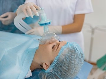 Medical professional administering anesthesia to patient on table