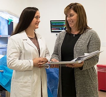 Kara Misto talking with nursing student while holding open binder