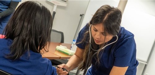 Two students taking blood pressure at the Workforce Development Hub