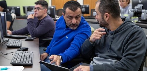 Two students discuss over computer