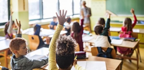 Children raising hands to answer teacher's question