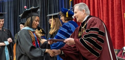 Graduate degree student receiving diploma from President Warner