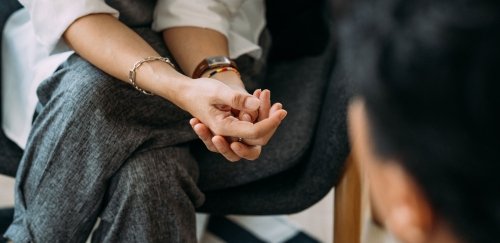 view of the arms of a person sitting with clasped hands